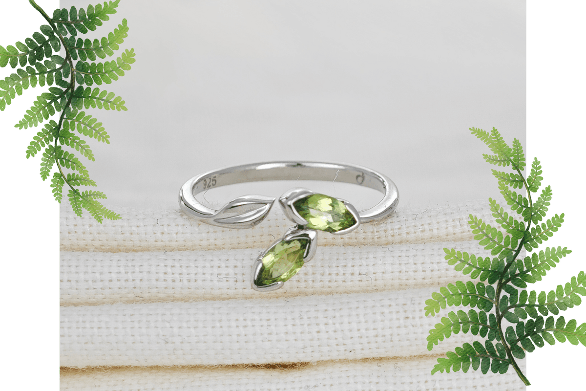 peridot silver adjustable ring on natural cloth background flagged by fern leaves