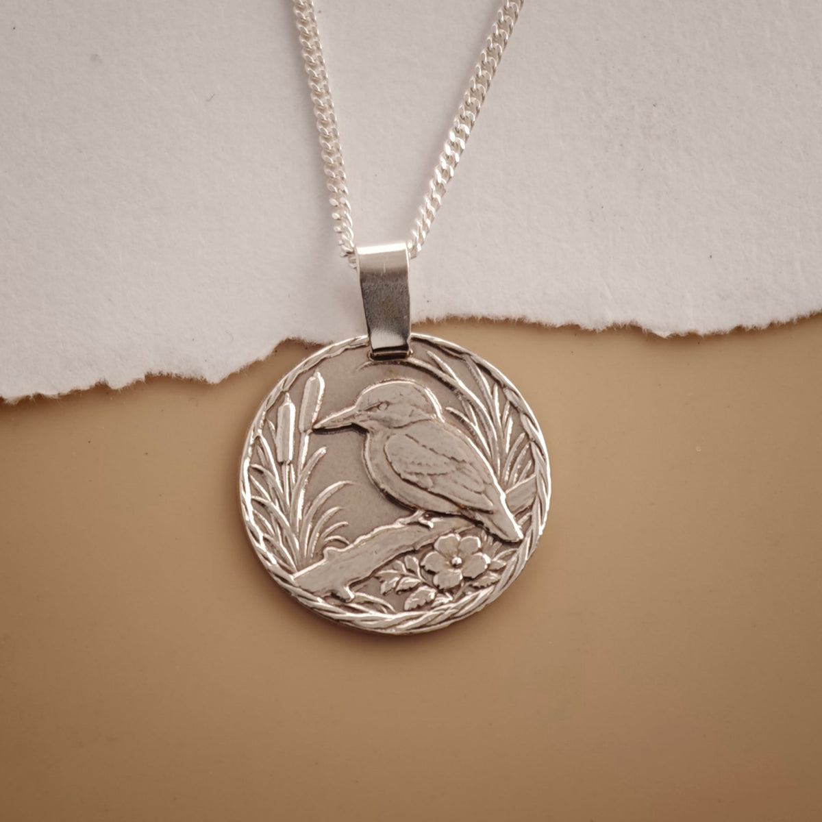 Kingfisher illustrated in silver on a disc coin pendant
