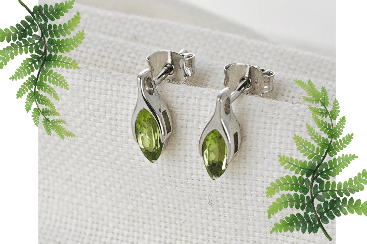 natural peridot minimalist earrings on cloth background flagged by fern leaves
