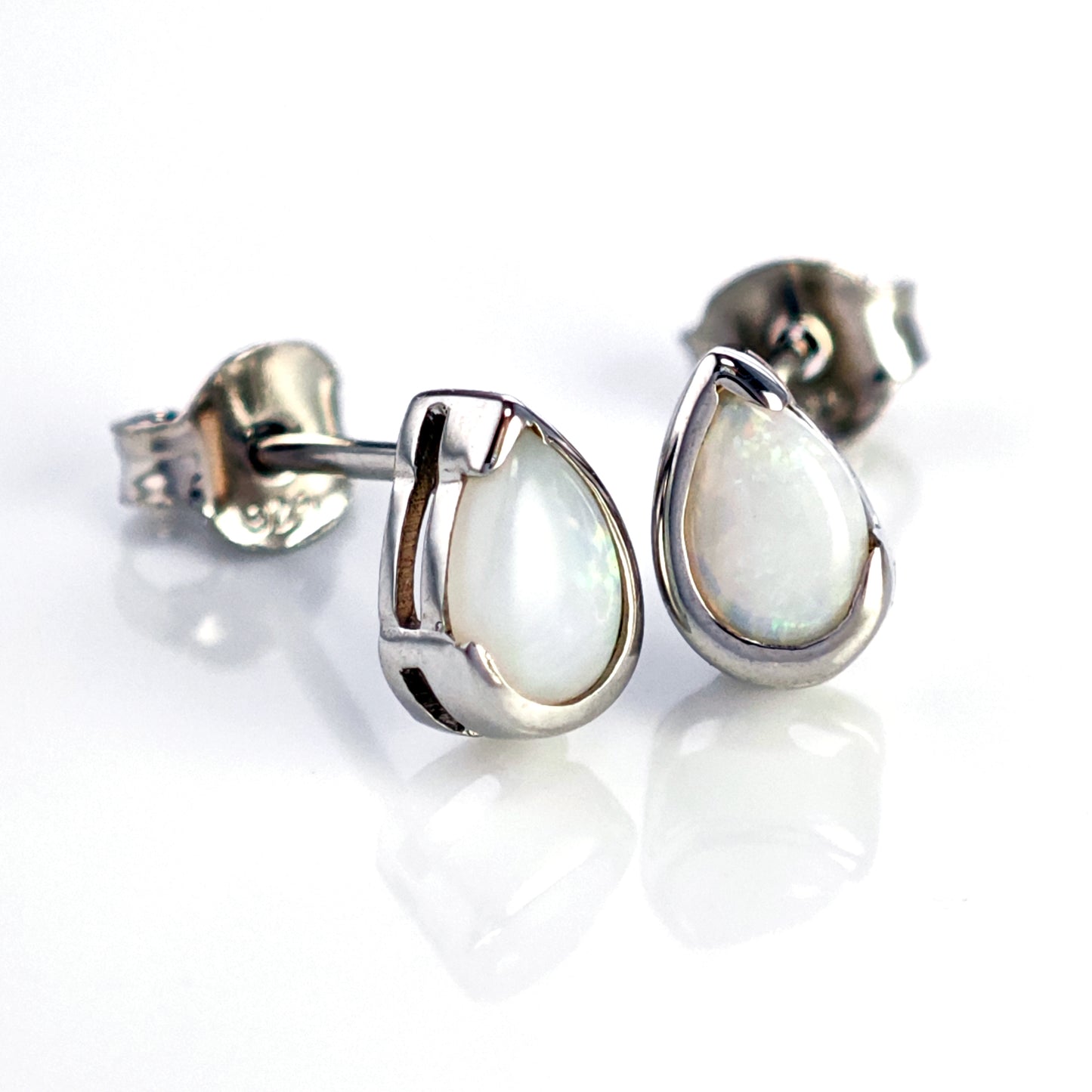 Teardrop-shaped silver earrings with a white gemstone on a white background