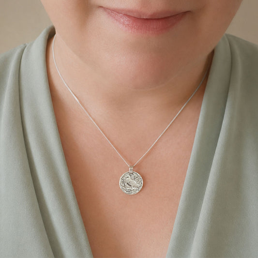 Model wearing the Pigeon engraved sterling silver coin pendant necklace, handcrafted in the UK from recycled sterling silver