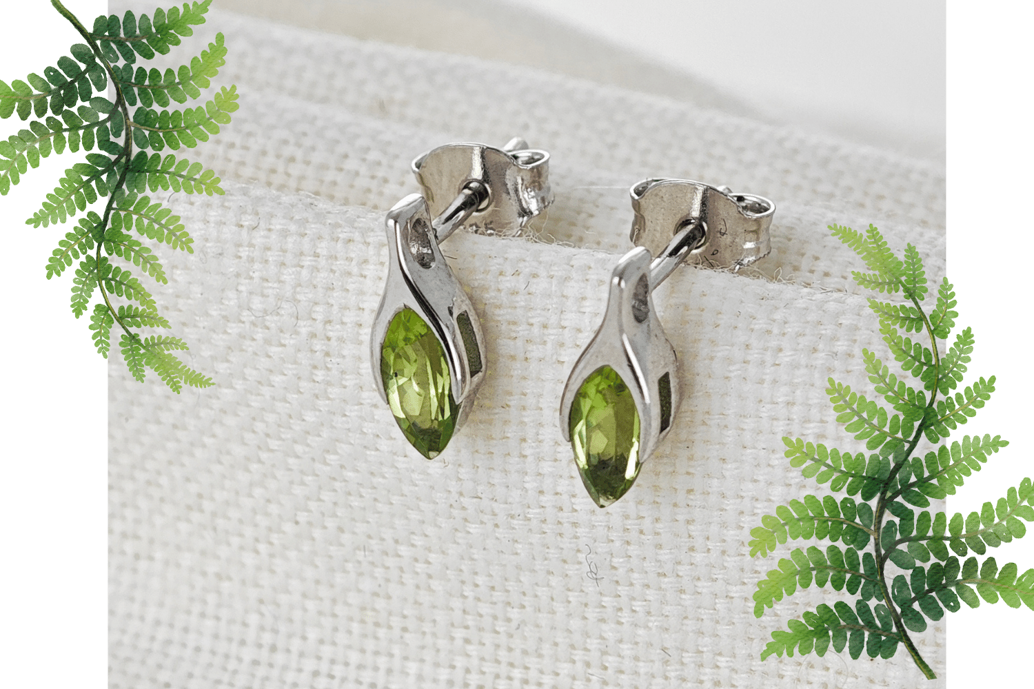 natural peridot minimalist earrings on cloth background flagged by fern leaves