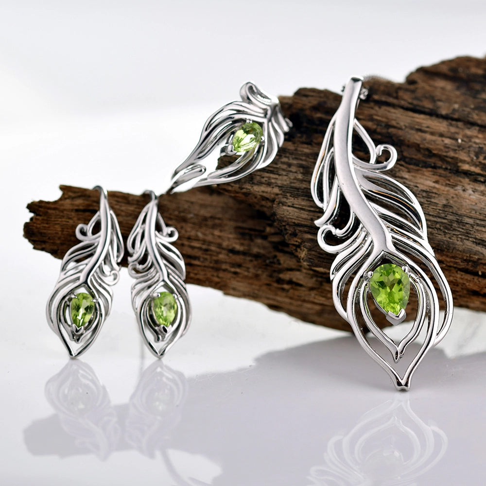 Peridot jewellery of a peacock feather design resting on a piece of drift wood