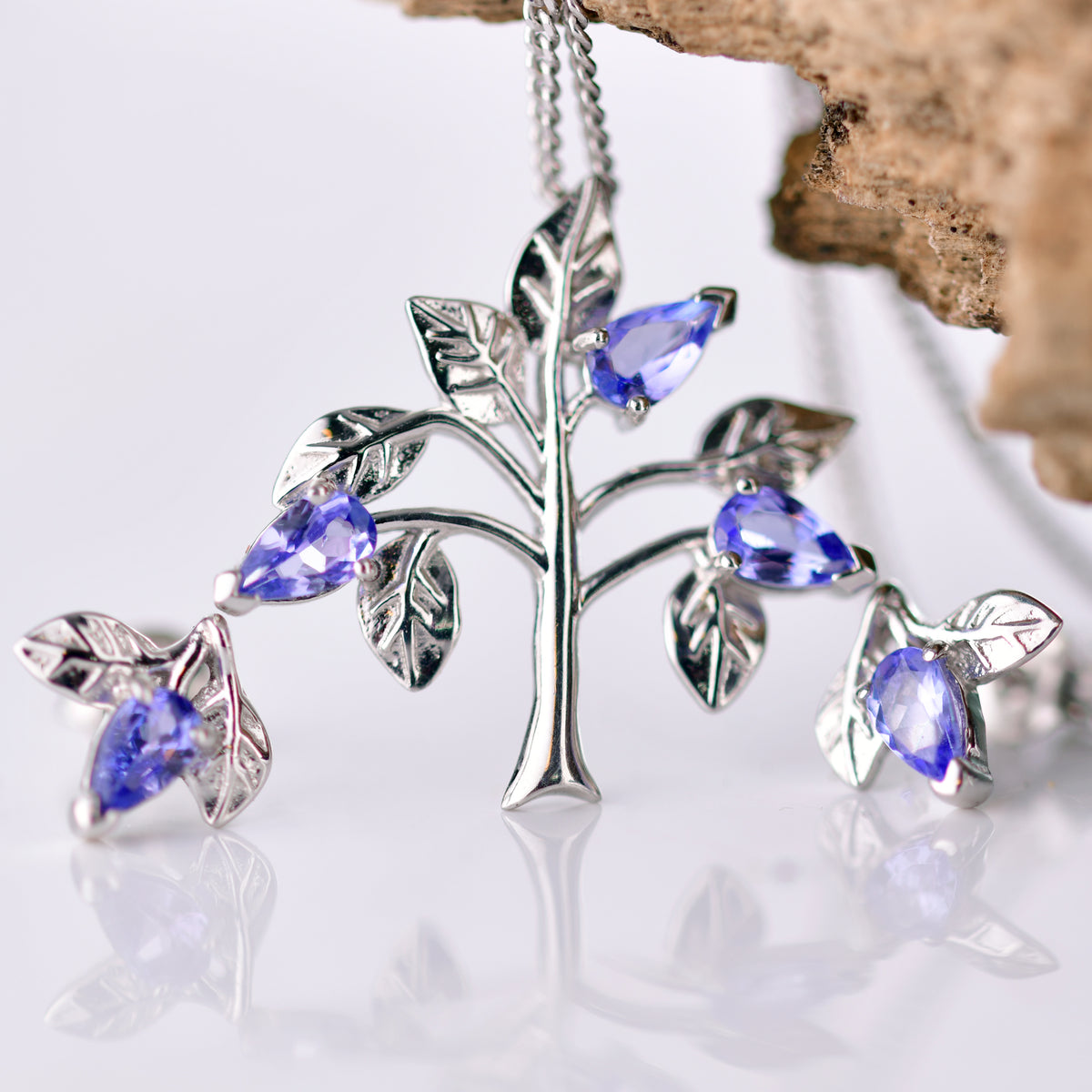 Natural Blue Tanzanite trilogy pendant in a tree shape with matching solitaire tanzanite lear earrings.  The set is a pendant on chain and stud earrings of sterling silver with a total of five tanzanites
