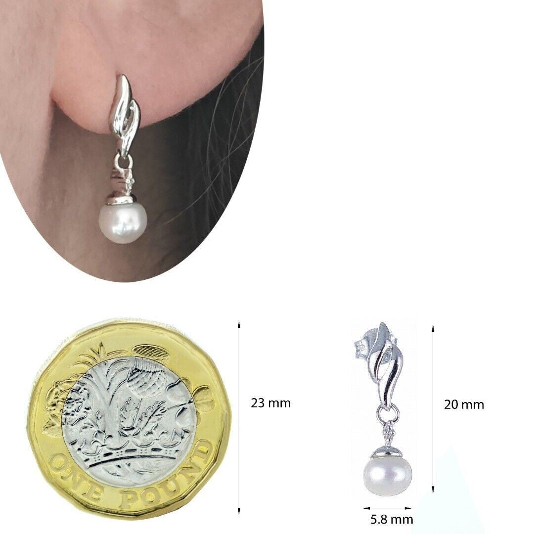 Silver pearl earrings with tiny diamond accent, freshwater pearls dangle style on ear and on white background against a coin for scale