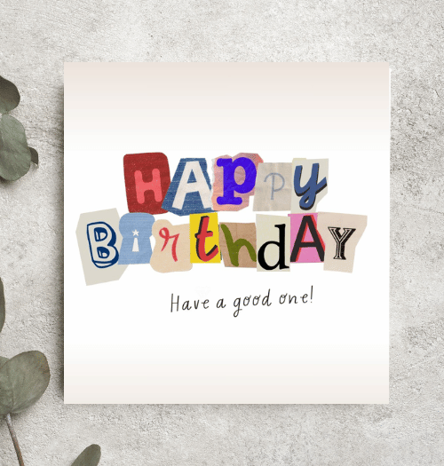Colorful 'Happy Birthday' card on a textured surface with leaves.
