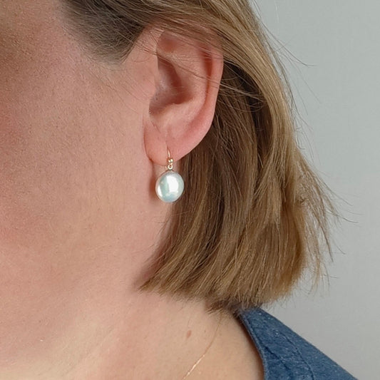gold pearl earrings, dangle coin shape shown on ear white background