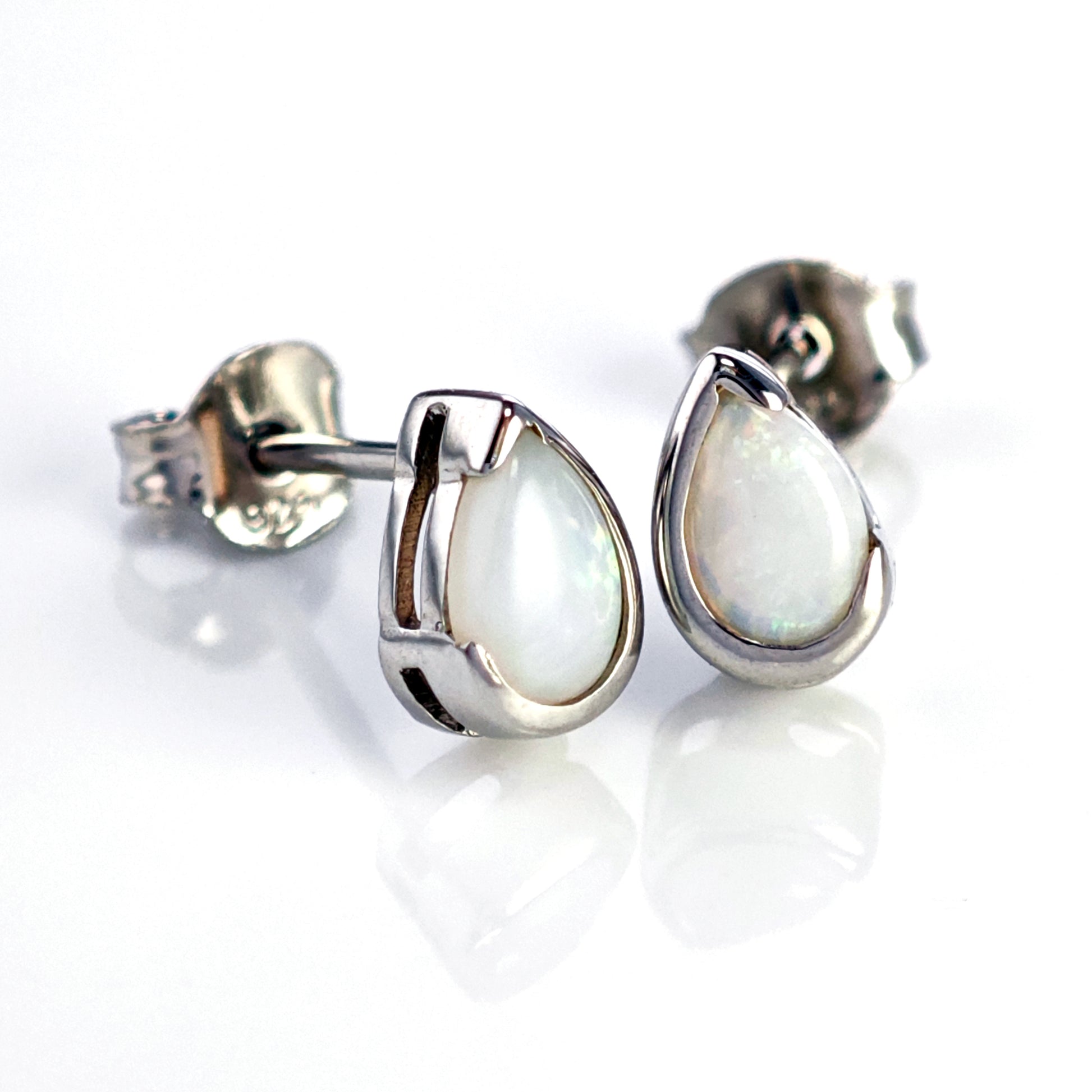 Teardrop-shaped silver earrings with a white gemstone on a white background
