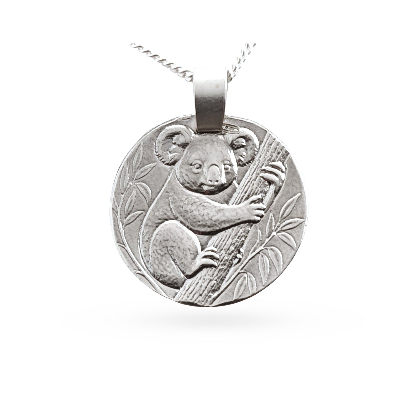 A round silver pendant necklace featuring an embossed koala clinging to a tree branch, suspended from a silver chain against a plain white background.