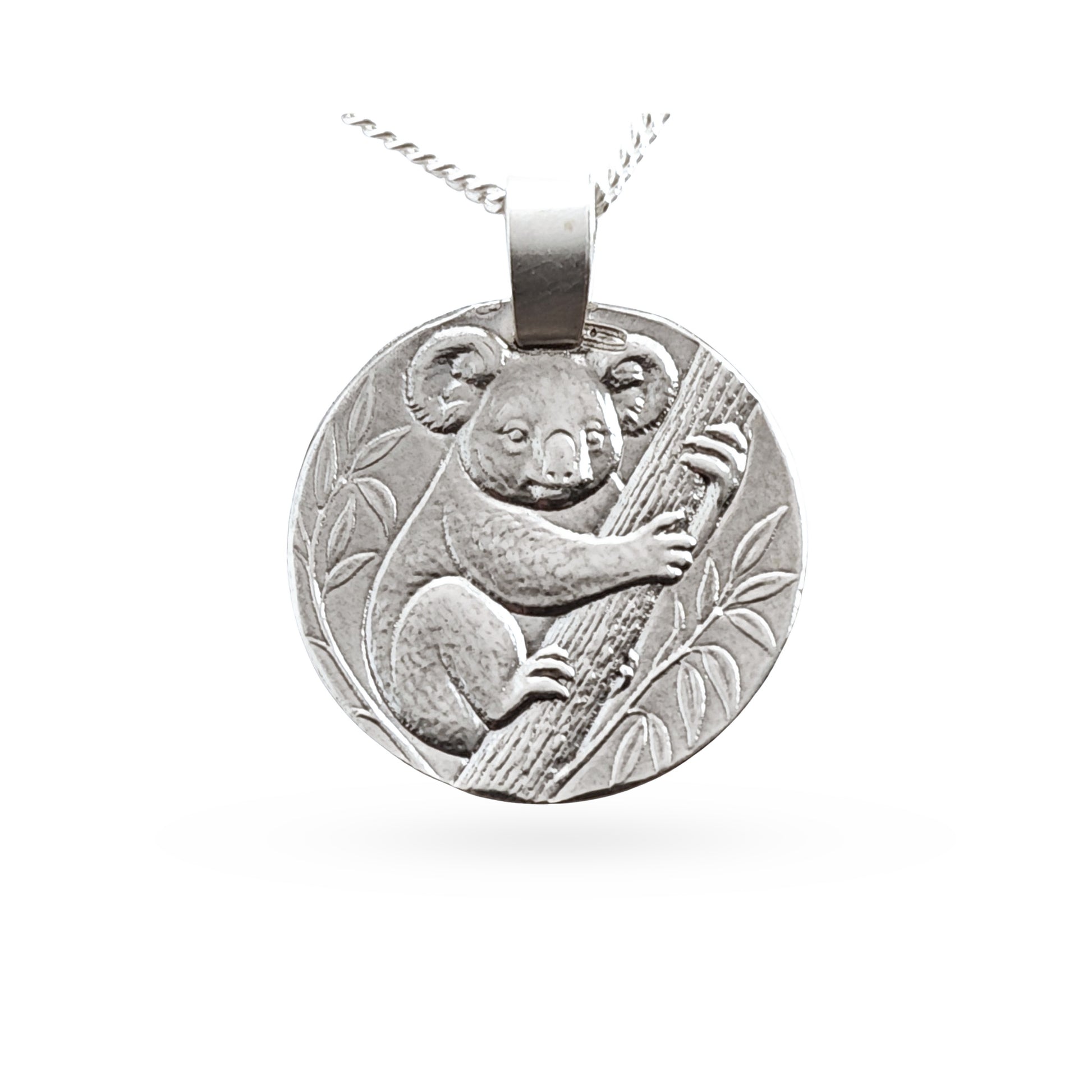 A round silver pendant necklace featuring an embossed koala clinging to a tree branch, suspended from a silver chain against a plain white background.