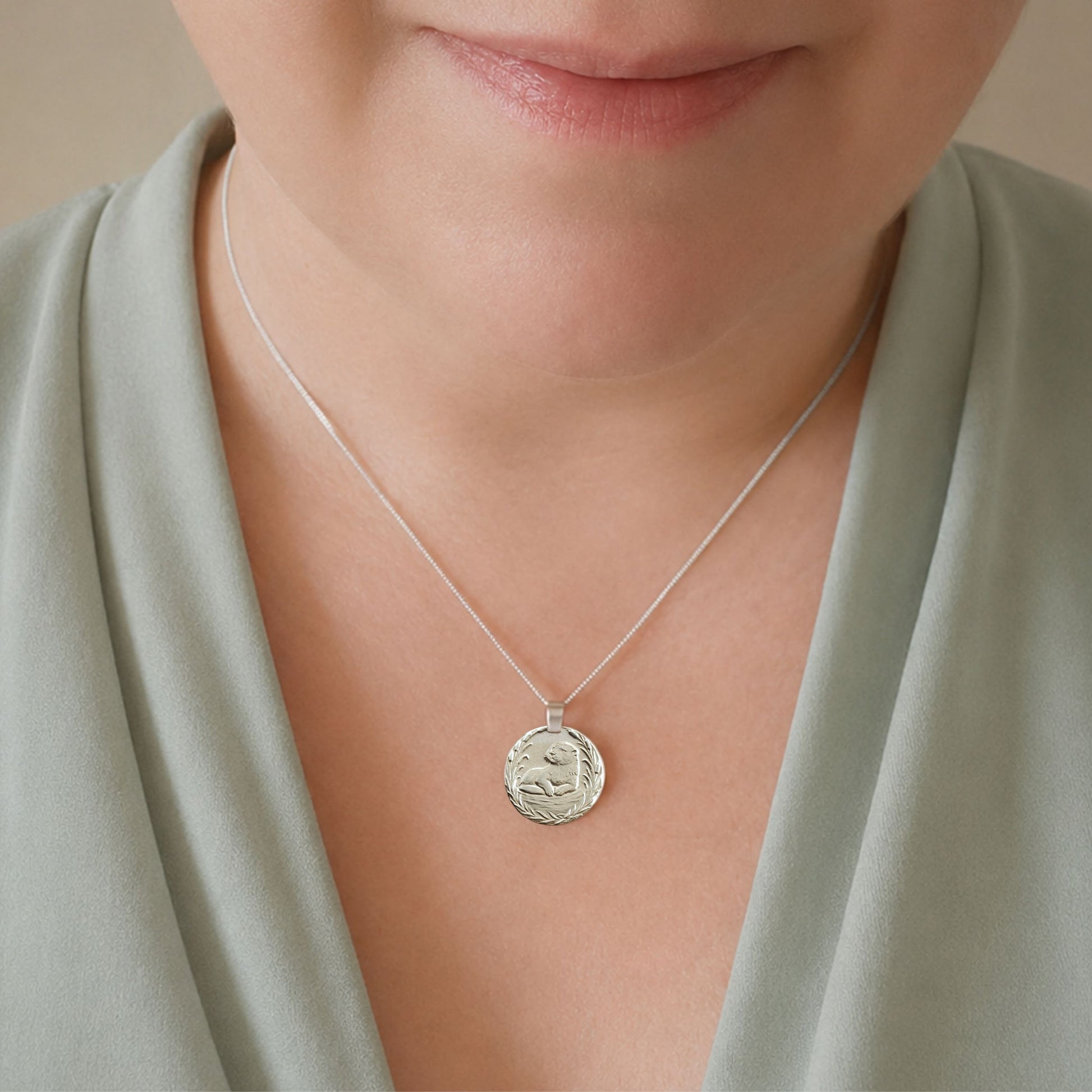 Model wearing the Otter engraved sterling silver coin pendant necklace, handcrafted in the UK from recycled sterling silver