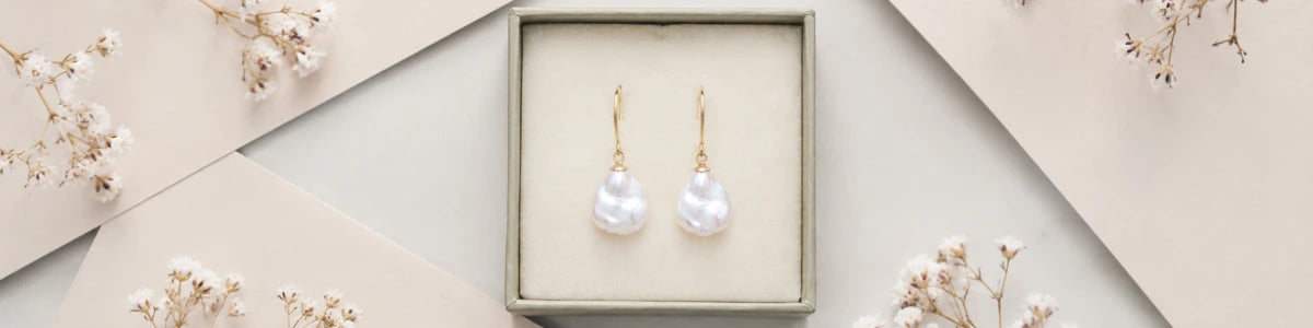 Pearl earrings in a box with a decorative background