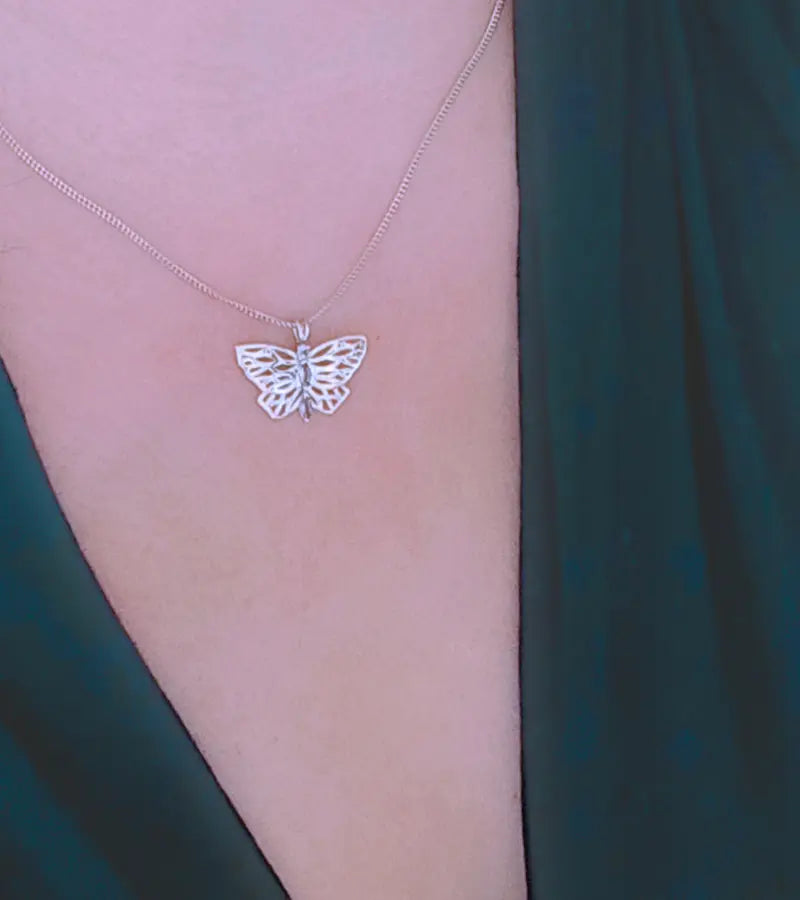 Silver butterfly necklace on a person's neck 
