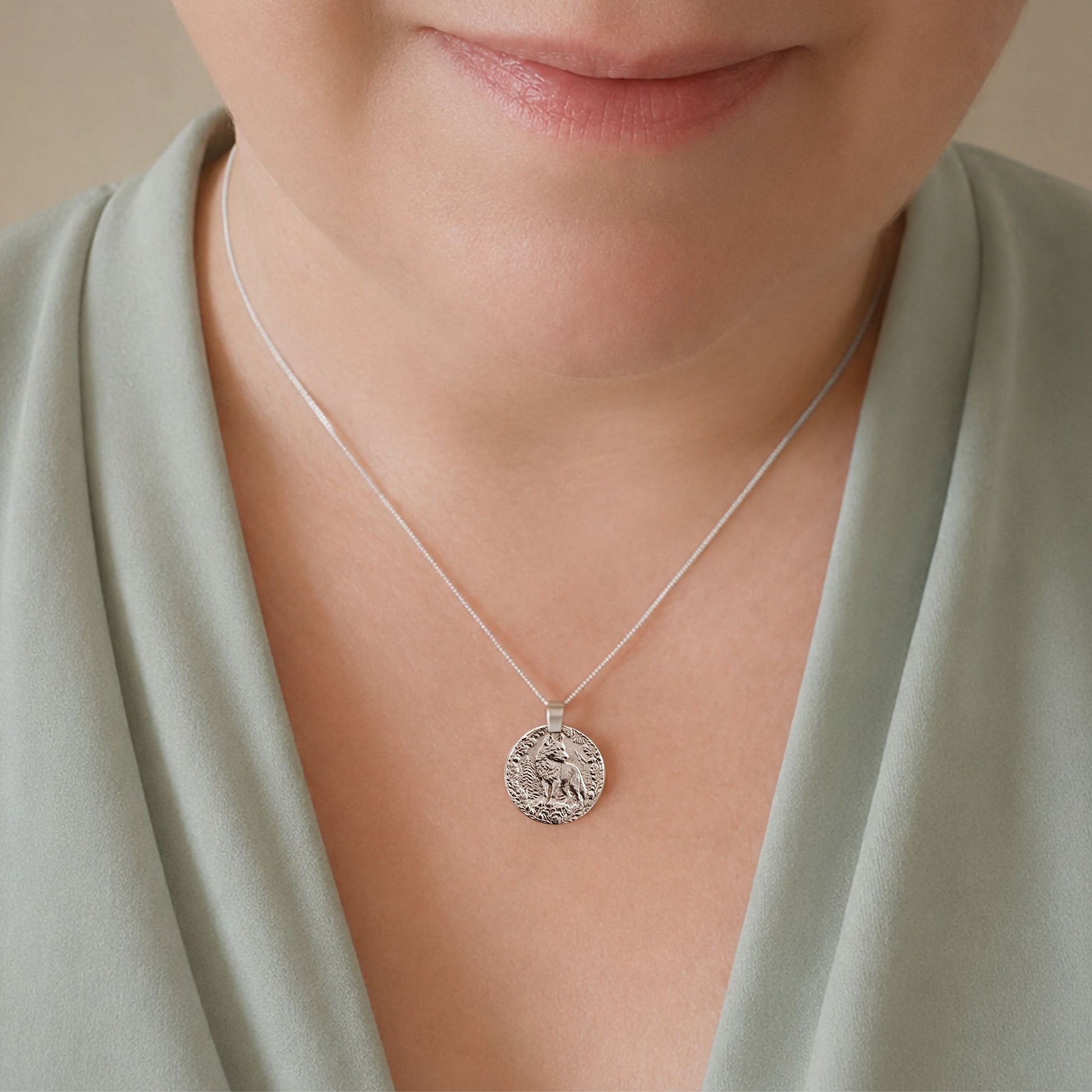 Model wearing the Wolf engraved sterling silver coin pendant necklace, handcrafted in the UK from recycled sterling silver